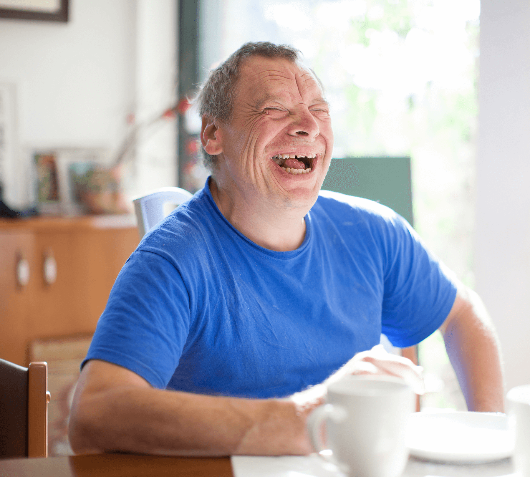 Man-in-a-blue-tshirt-sitting-at-a-dining-table-with-a-cup-of-coffee