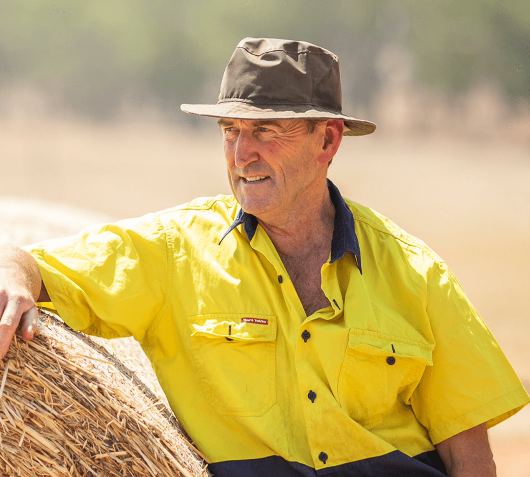 A-farmer-resting-his-arm-on-a-hay-bale-with-a-concerned-look-on-his-face