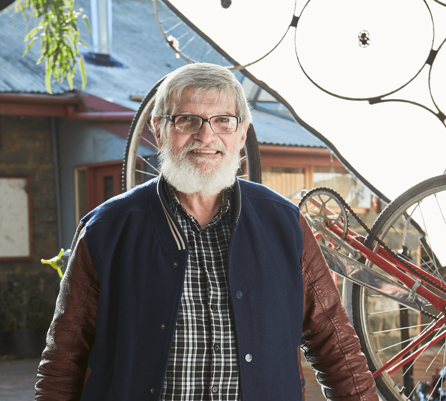 A-man-in-a-bomber-jacket-wearing-glasses-standing-next-to-an-overturned-bicycle