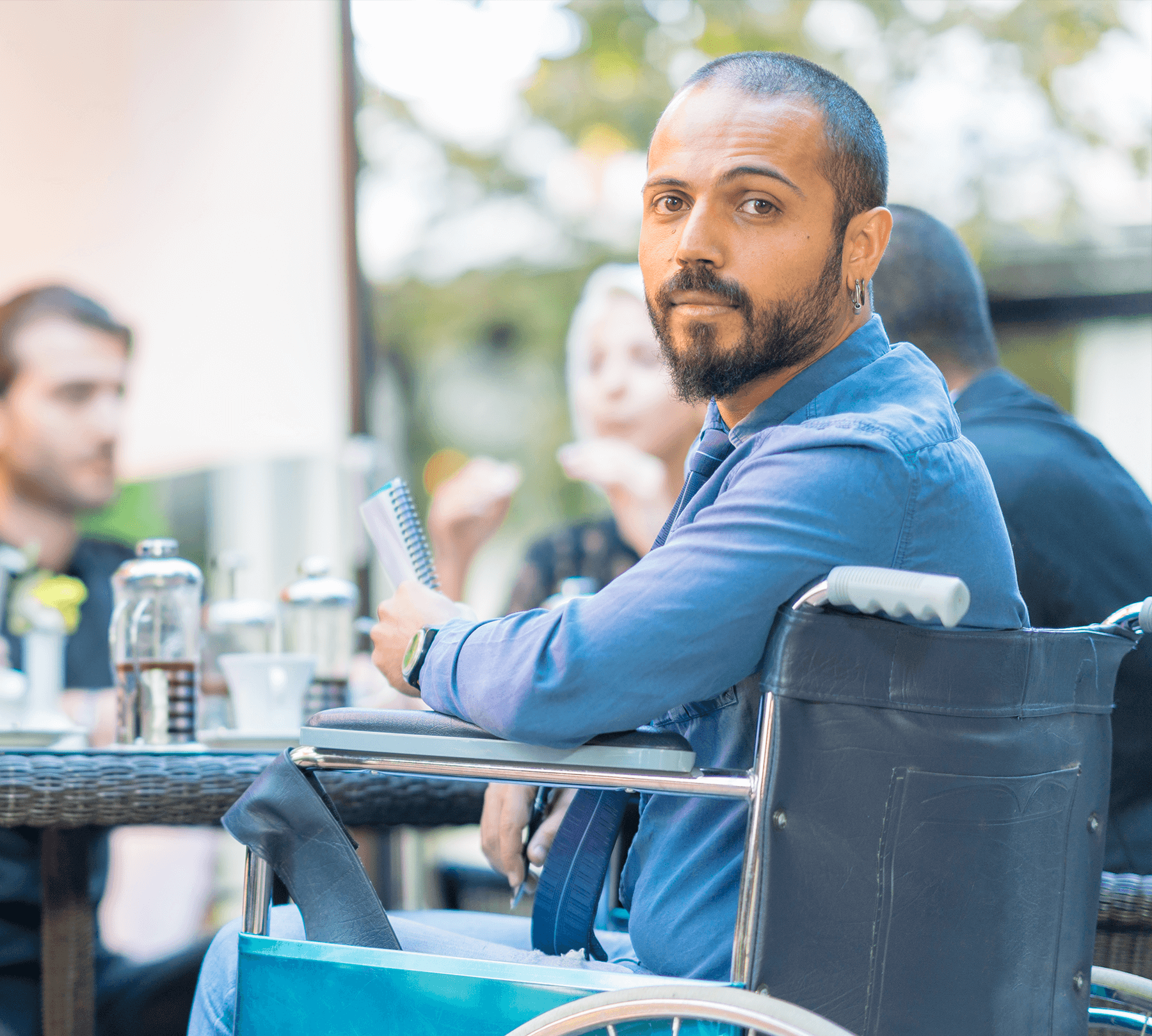 A-man-using-a-wheel-chair-holding-a-notebook-looking-forward
