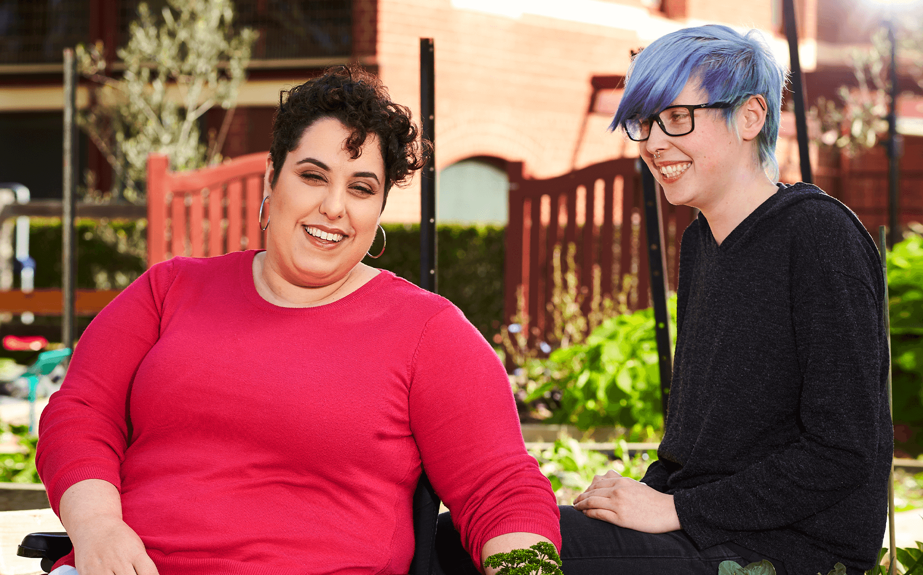 A-woman-in-a-bright-pink-top-in-working-in-a-community-garden-with-her-support-worker