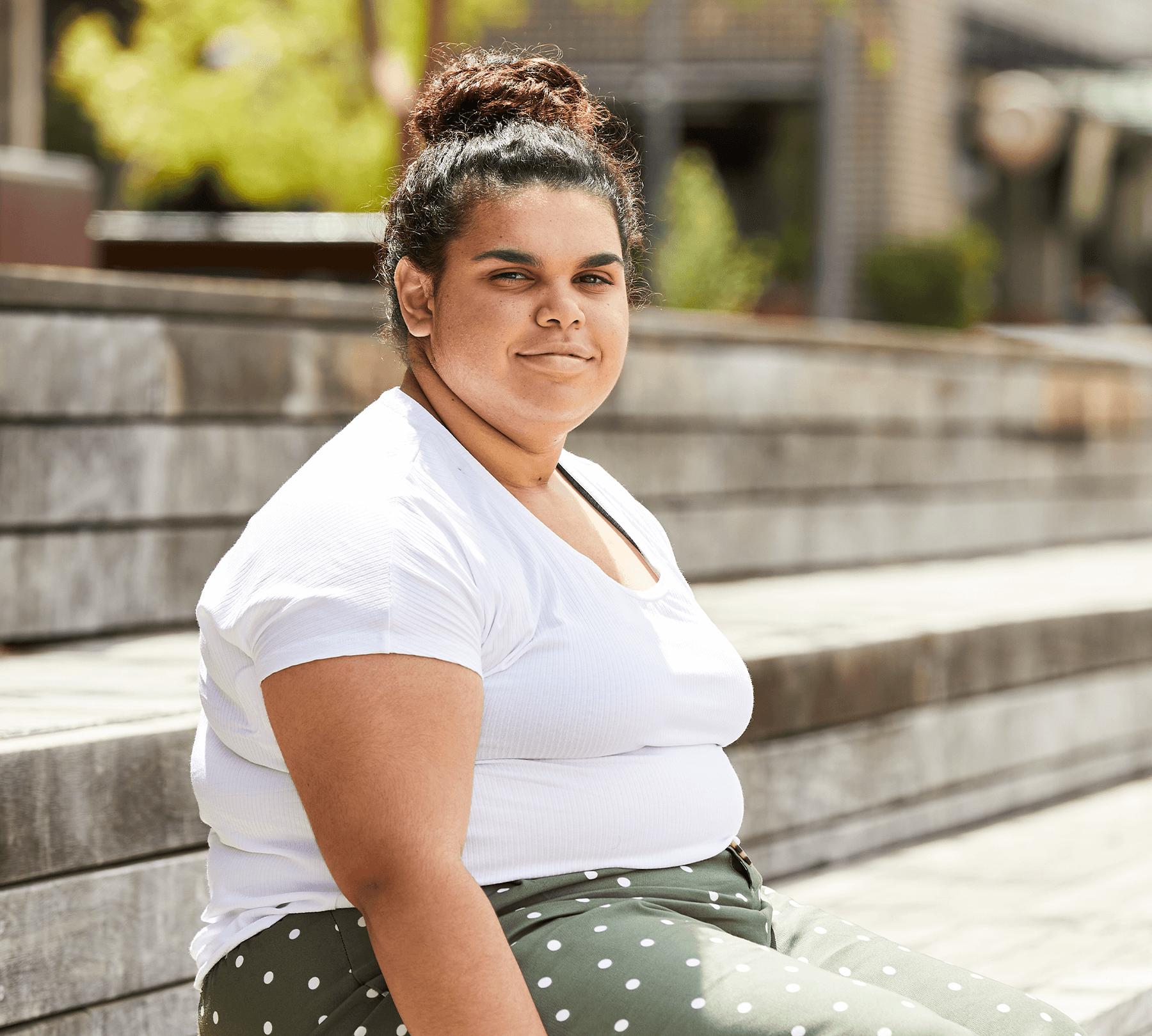 A-woman-in-a-white-t-shirt-and-gren-polka-dot-pants-sitting-on-wooden-stairs